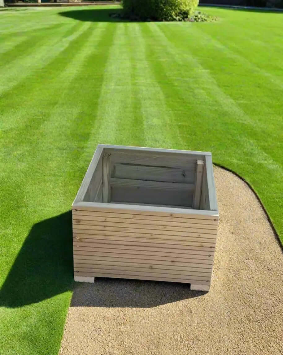 40cm Square Wooden Decking garden Planter on a lawn with neat grass and a sandy edge.